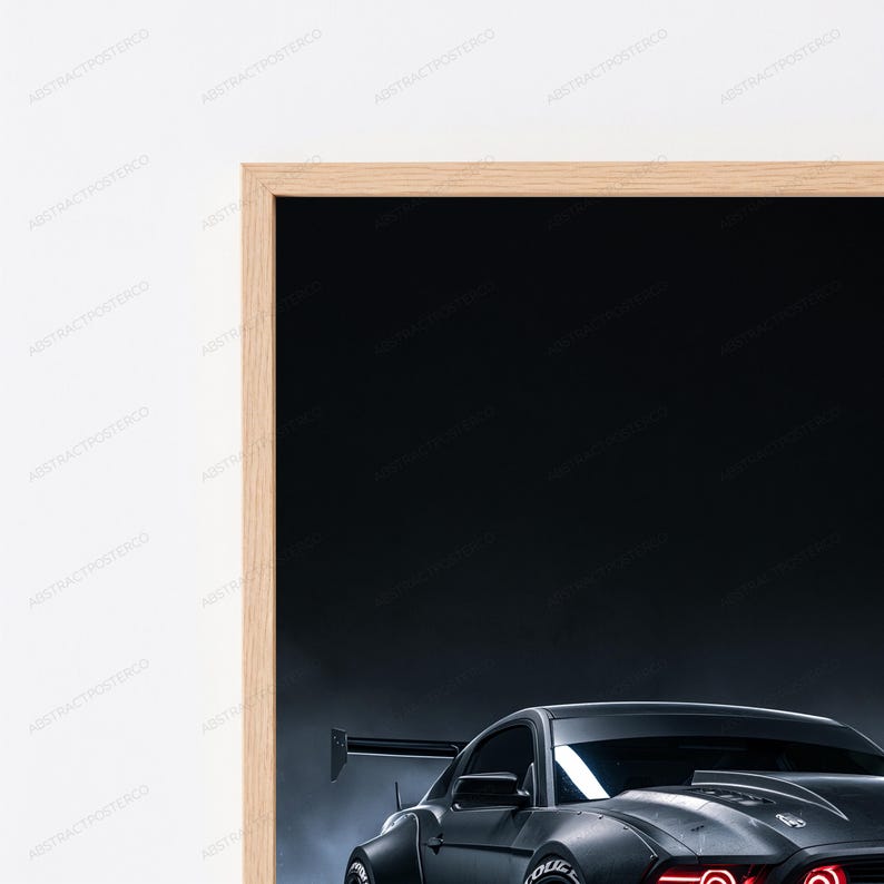 May include: A framed wall art print featuring a dark grey sports car with a prominent rear spoiler and glowing red headlights against a dark, smoky background. The artwork is enclosed in a light-toned wooden frame, showcasing a sleek automotive design.