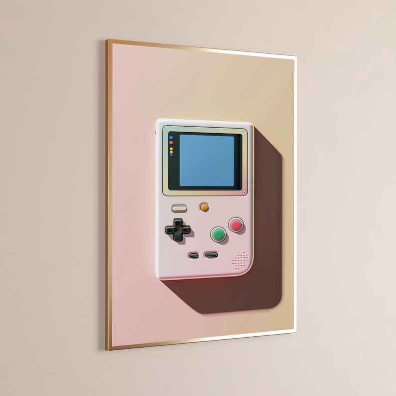 May include: A framed wall art print featuring a light-coloured handheld video game console with a blue screen, a black directional pad, a green button, a red button, and two small grey buttons, set against a soft gradient peach-toned background.
