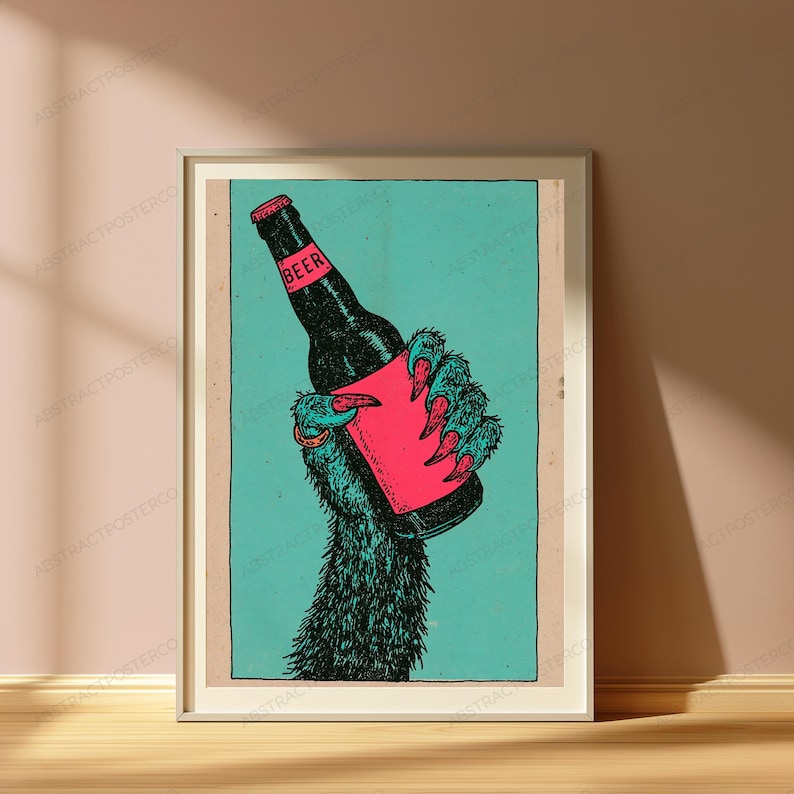 May include: A framed art print featuring a dark, furry creature hand with sharp claws holding a black beer bottle. The bottle has a pink label with the word BEER printed in black. The background is a solid teal colour within a rectangular border.