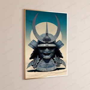 May include: A framed wall art print featuring a blue-toned samurai helmet with a large crescent-shaped crest and a fierce facial mask. The helmet is centered against a pale yellow circular background and a textured, sandy-colored ground surface.