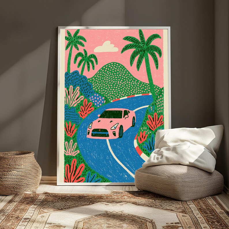 May include: A framed art print featuring a pink sports car driving along a winding blue road. The scene includes green palm trees, pink coral-like plants, a textured green mountain, and a single white cloud against a solid pink sky background.