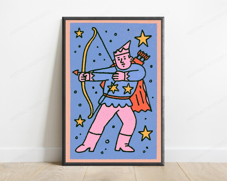 May include: A framed wall art print featuring a cartoon archer character with a pink hat, shirt, and pants, wearing a red cape. The character holds a yellow bow and arrow against a blue background filled with yellow stars and black dots.