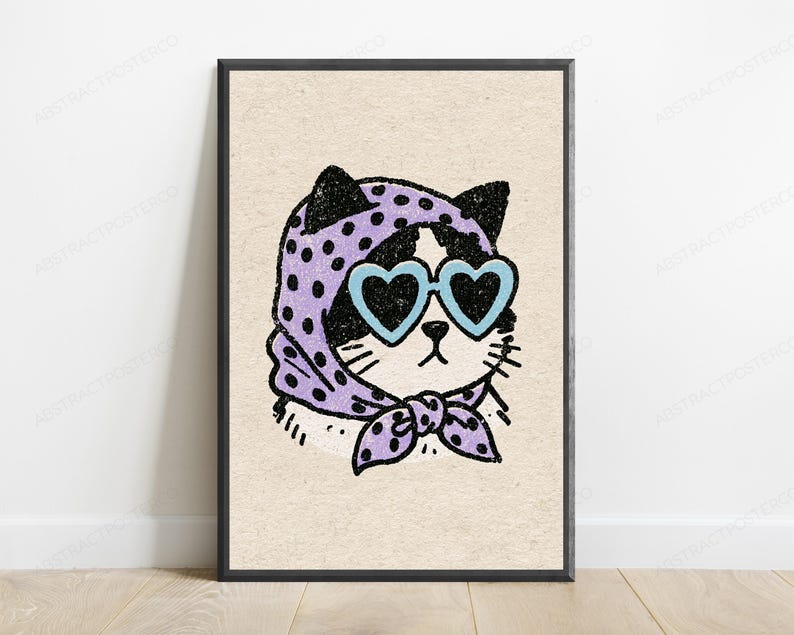 Pu&ograve; includere: Una stampa artistica incorniciata su sfondo beige chiaro con l'illustrazione di un gatto bianco e nero. Il gatto indossa un foulard viola a pois neri annodato sotto il mento e occhiali da sole azzurri a forma di cuore con lenti nere.