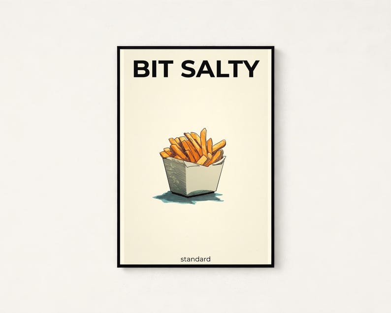 May include: A rectangular wall art print with a cream background and a thin black frame. The text BIT SALTY appears in black at the top, with a drawing of golden-brown french fries in a white container below and the word standard at the bottom.