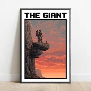 May include: A framed pixel art print titled THE GIANT, featuring a large stone-like figure standing on a cliff edge overlooking a sunset sky with orange and red clouds. A small silhouette of a person stands nearby on the rocky ledge.