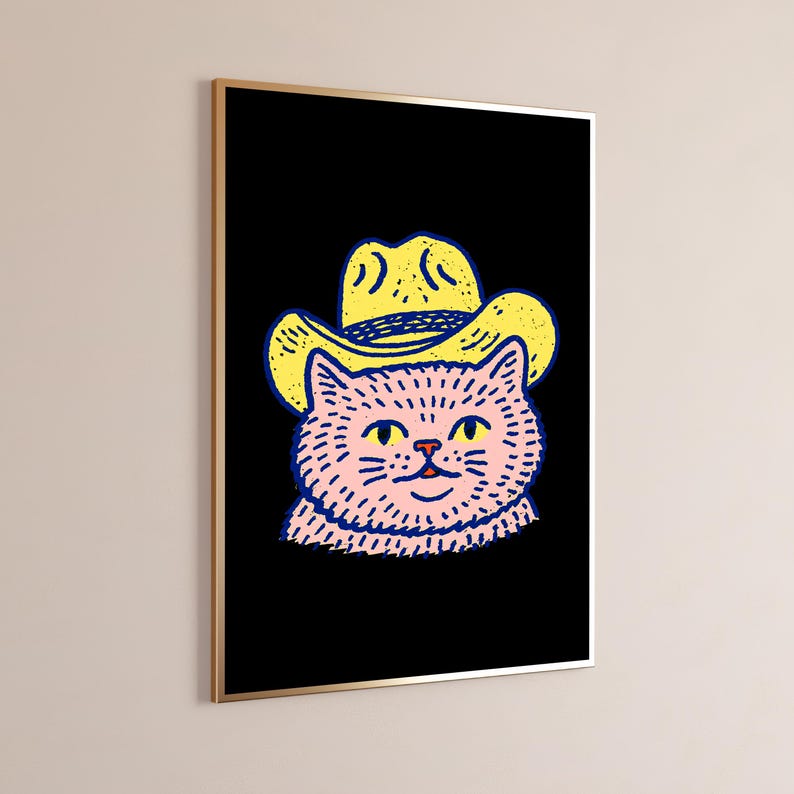 Puede incluir: Una impresi&oacute;n de arte mural enmarcada que presenta una ilustraci&oacute;n gr&aacute;fica de un gato rosa con un sombrero de vaquero amarillo sobre un fondo negro s&oacute;lido. El gato tiene ojos amarillos y contornos azul oscuro, en un marco met&aacute;lico fino.