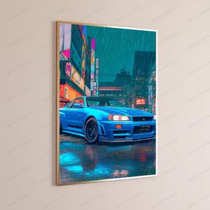 May include: A framed wall art print featuring a bright blue sports car parked on a wet city street at night. The scene is illuminated by vibrant neon signs in shades of pink, orange, and yellow, with rain falling against a dark teal background.