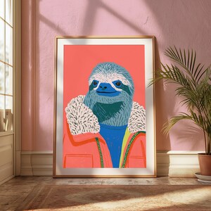 May include: A framed art print featuring a stylized illustration of a sloth with blue fur wearing a bright coral jacket with a white faux-fur collar over a blue sweater, set against a solid coral background with a clean white border.