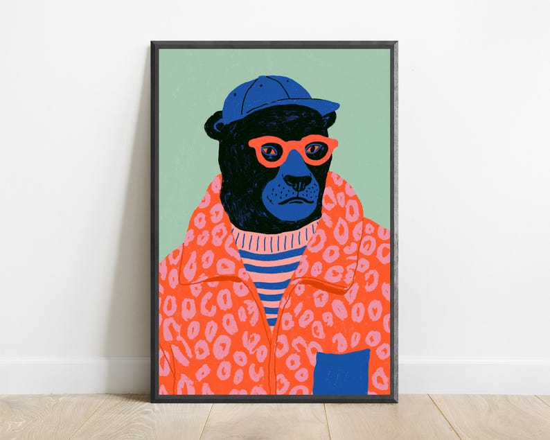 May include: A framed art print featuring a black panther wearing a blue baseball cap, bright orange glasses, a blue and pink striped sweater, and an orange leopard print jacket with a blue pocket, set against a solid light green background.