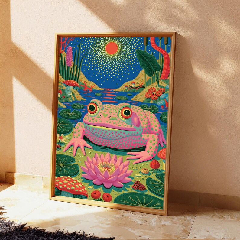 Op de afbeelding: Een ingelijste rechthoekige wandkunstprint met een levendige, kleurrijke illustratie van een grote roze en groen gevlekte kikker die in een vijver zit. De sc&egrave;ne bevat een heldere oranje zon, een bloeiende roze lotusbloem, waterlelies en rode paddenstoelen.