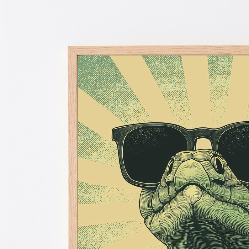 May include: A framed graphic art print featuring a green snake wearing large black sunglasses. The background consists of a pale yellow sunburst pattern with a stippled texture. The frame is made of light-colored wood with a visible grain.