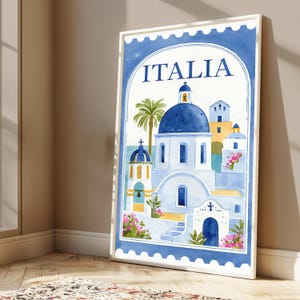 May include: A framed vertical wall art print featuring a watercolor illustration of Mediterranean architecture with blue domes, white buildings, and a palm tree. The text ITALIA is printed at the top. The border resembles a postage stamp edge.