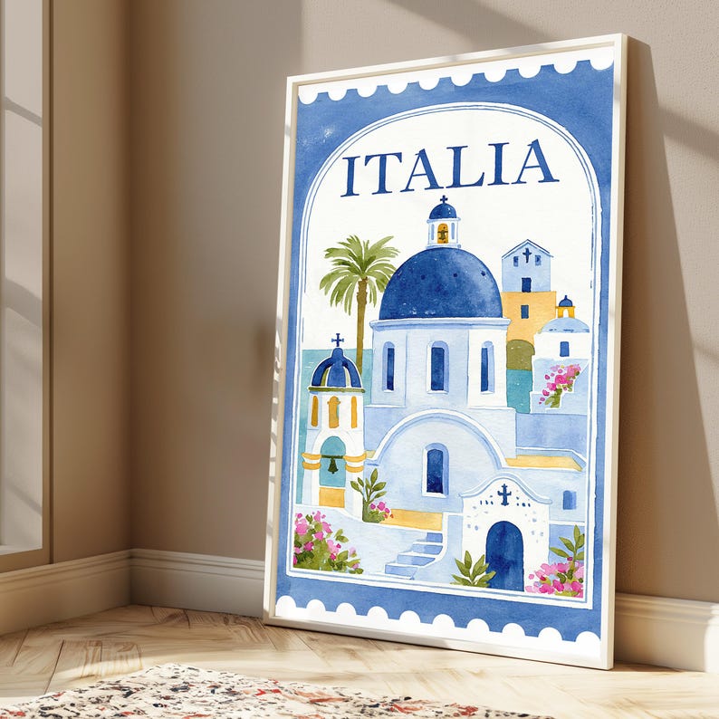 May include: A framed vertical wall art print featuring a watercolor illustration of Mediterranean architecture with blue domes, white buildings, and a palm tree. The text ITALIA is printed at the top. The border resembles a postage stamp edge.