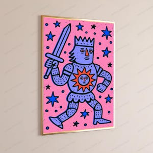 May include: A rectangular wall art print in a gold frame featuring a stylized illustration of a purple knight wearing a crown and holding a sword. The knight has a sun emblem on the chest and is set against a bright pink background with blue stars.