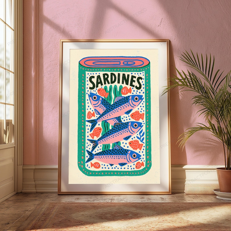 May include: A framed wall art print featuring a stylized illustration of a tin of sardines. The design displays three blue and pink fish stacked vertically, surrounded by small orange fish and green seaweed, with the text SARDINES at the top.