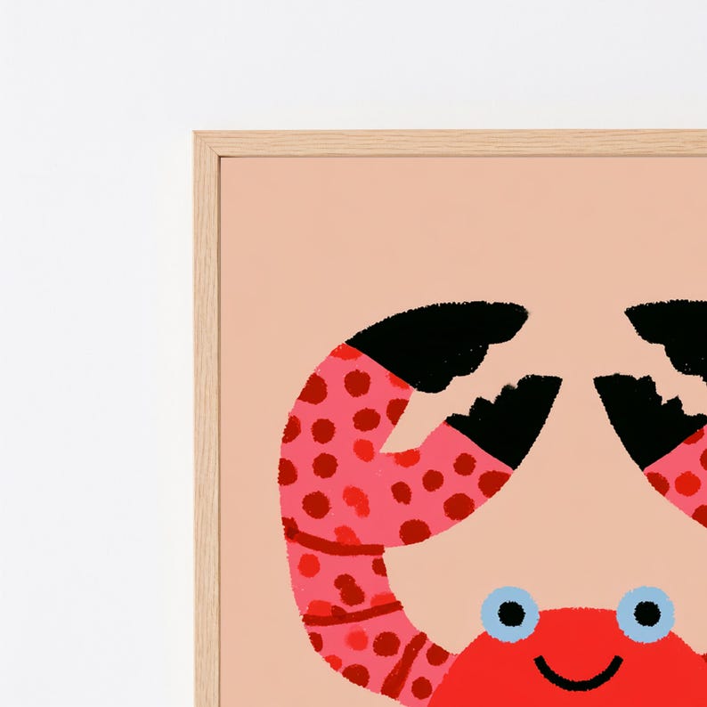 May include: A framed wall art print featuring a stylized crab illustration on a light peach background. The crab has a bright red body, light blue eyes, and pink pincers covered in dark red polka dots with black tips, all encased in a light wood frame.