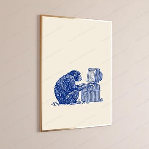 May include: A framed wall art print featuring a blue ink-style illustration of a chimpanzee sitting and typing on a vintage desktop computer. The artwork is set against a solid cream-colored background, presented in a thin gold-toned frame.