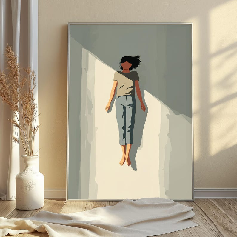 May include: A framed wall art print featuring a stylized illustration of a person with dark hair wearing a gray t-shirt and blue pants, floating in a vertical beam of light against a muted sage green background with sharp geometric shadows.