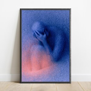 May include: A framed vertical wall art print featuring a textured, deep blue figure sitting with their head in their hands. The figure is composed of dense, scribbled lines, with a soft, glowing pink light emanating from the lower portion of the image.