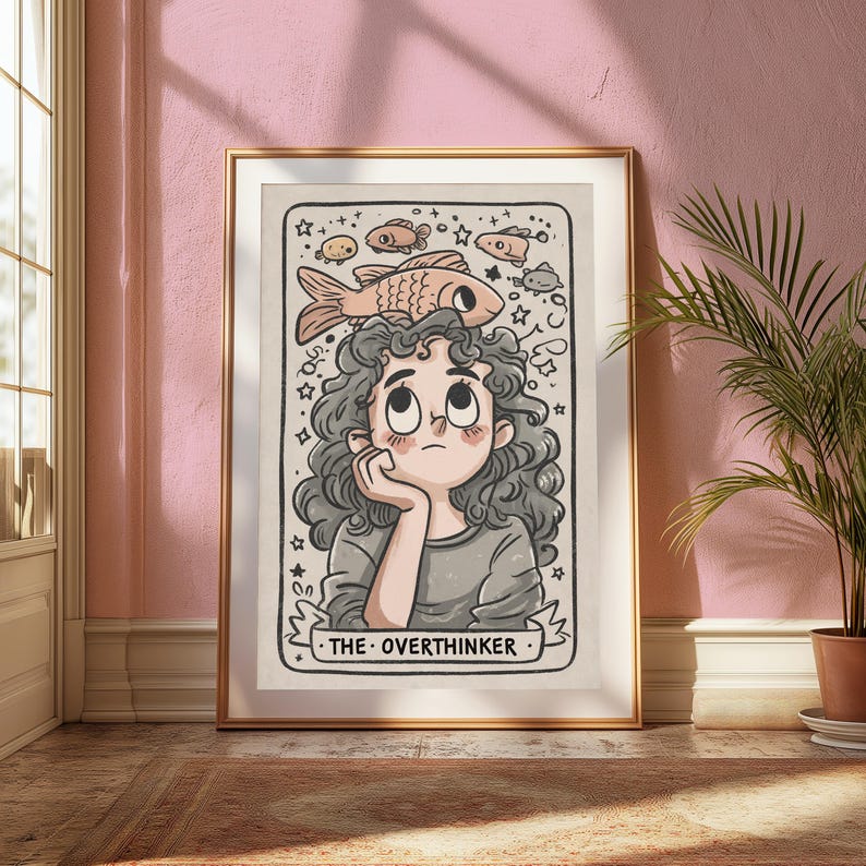 May include: A framed wall art print featuring a cartoon illustration of a person with curly hair resting their chin on a hand, looking up at a large fish. The text THE OVERTHINKER is printed at the bottom. The art includes small stars and fish.
