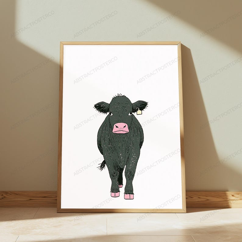 May include: A framed wall art print featuring a centered illustration of a dark charcoal-colored cow with a pink nose and hooves. The cow is depicted in a front-facing stance, wearing a small, light yellow ear tag on its right ear.