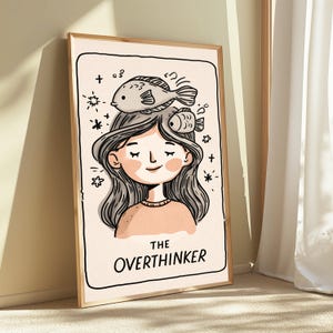 K&ouml;nnte beinhalten: Ein gerahmter Kunstdruck mit einer Cartoon-Illustration einer Person mit langem, welligem Haar und zwei Fischen auf dem Kopf. Der Hintergrund ist cremefarben mit kleinen Sternakzenten. Darunter steht der Text THE OVERTHINKER.