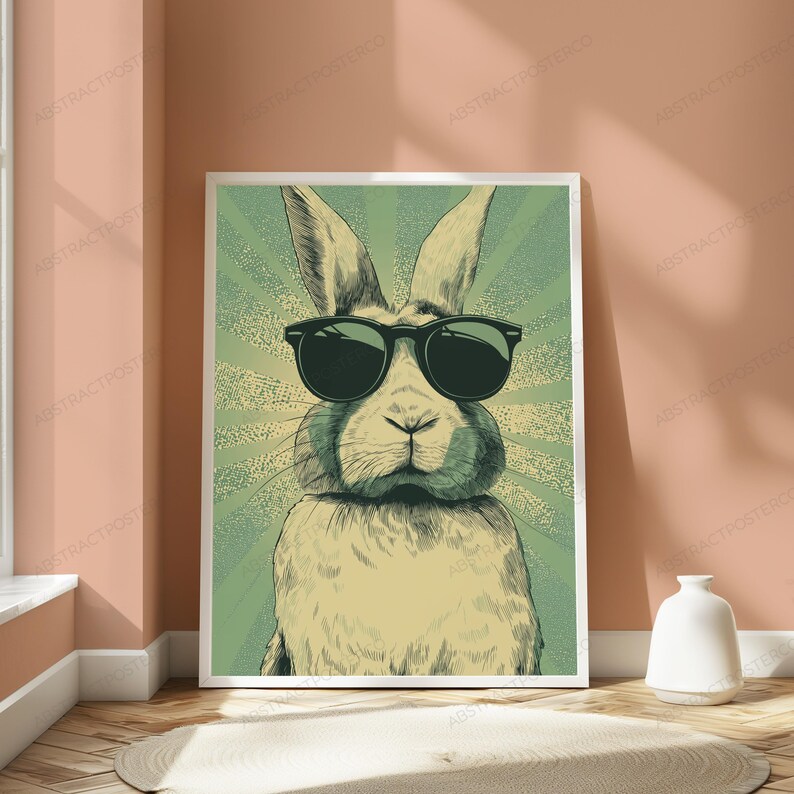 May include: A rectangular wall art print featuring a stylized illustration of a rabbit wearing black sunglasses. The rabbit is centered against a green background with a radiating sunburst pattern. The artwork uses a muted color palette.
