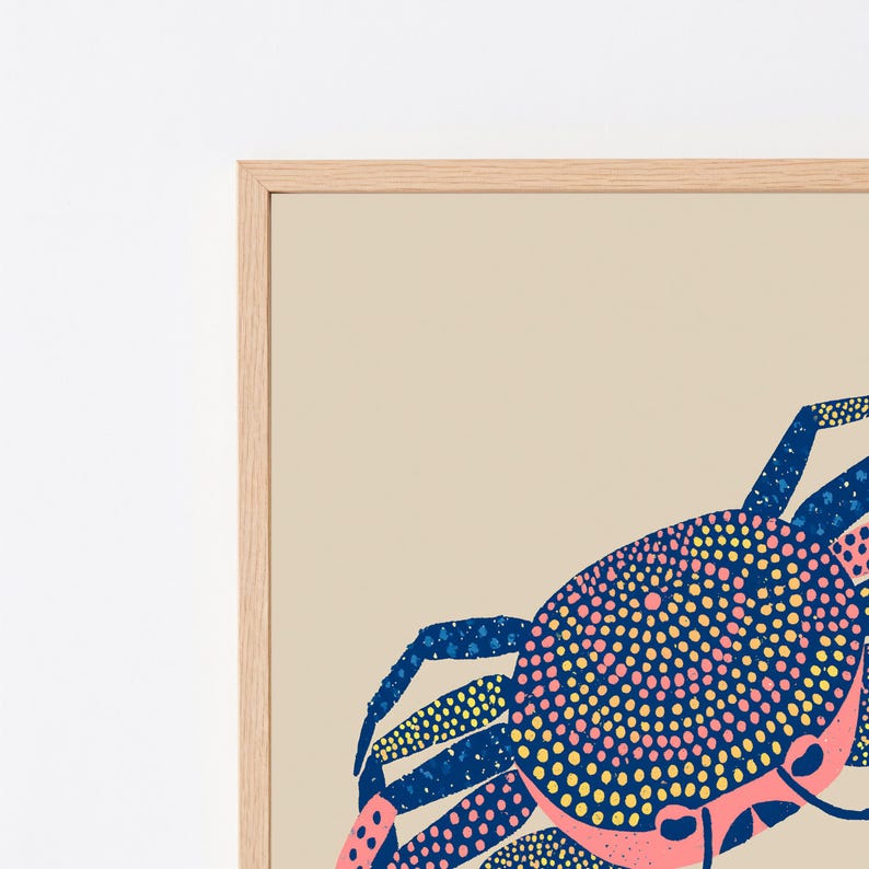May include: A framed wall art print featuring a stylized crab illustration on a light beige background. The crab is rendered in a dotted pattern using a color palette of dark blue, bright pink, and yellow, set within a light wood frame.