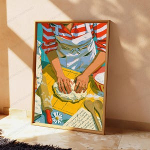 K&ouml;nnte beinhalten: Ein gerahmter Kunstdruck, der eine Person in einem rot-wei&szlig; gestreiften Hemd und einer wei&szlig;en Sch&uuml;rze zeigt, die Teig auf einer gelben Fl&auml;che knetet. Die Szene umfasst ein Nudelholz, eine Sch&uuml;ssel mit Mehl, zwei Holzl&ouml;ffel und eine Rezeptnotiz.