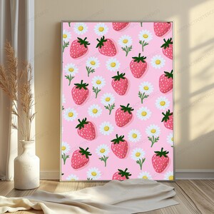 May include: A rectangular wall art print featuring a repeating pattern of red strawberries with green leaves and white daisies with yellow centers on a solid light pink background. The artwork is framed in a thin metallic border.