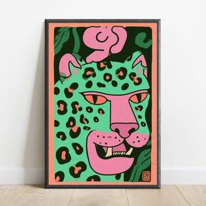 May include: A framed rectangular art print featuring a stylized leopard illustration. The leopard has a mint green face with black spots, a pink snout, and orange eyes. It is set against a dark green background with a coral pink border.