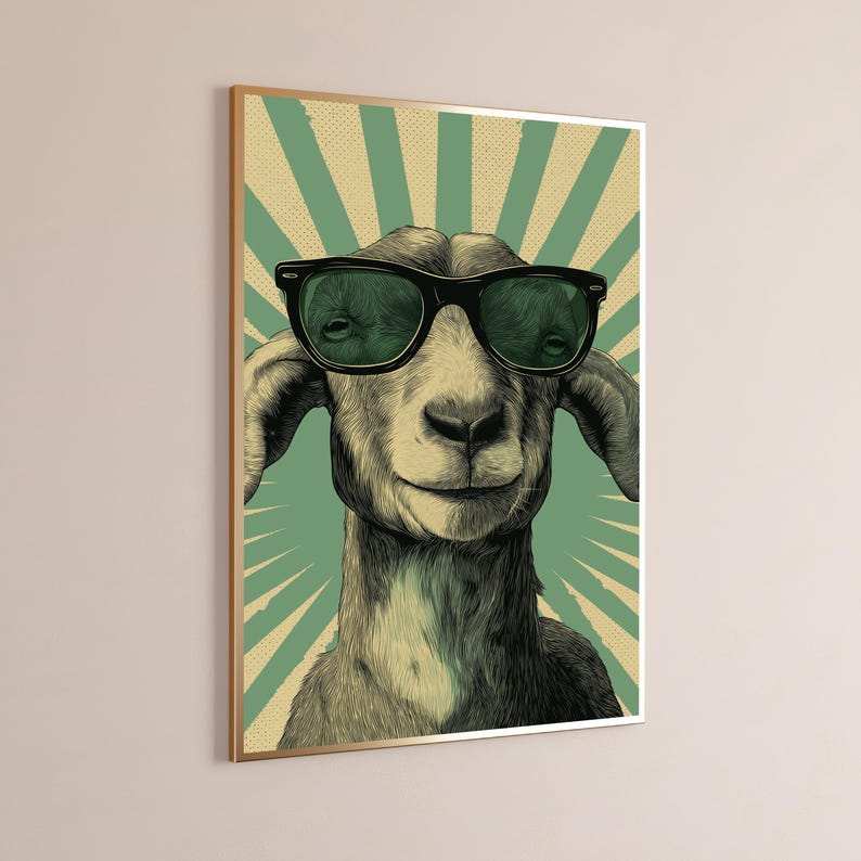 May include: A framed wall art print featuring a detailed illustration of a goat wearing black-rimmed sunglasses. The goat is centred against a background of radiating light green and cream-coloured sunburst rays with a subtle dot pattern.