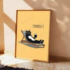 May include: A framed poster featuring a yellow background with a black and white cat wearing yellow sunglasses, lounging on a wooden beach chair while holding a dark beverage. The text PURRRFECT is printed in black above the cat illustration.