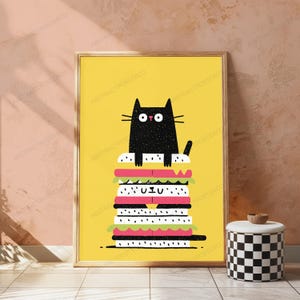 May include: A framed wall art print featuring a black cat with wide eyes sitting atop a tall, multi-layered sandwich illustration against a solid yellow background. The sandwich includes layers of white bread, pink meat, and green lettuce.
