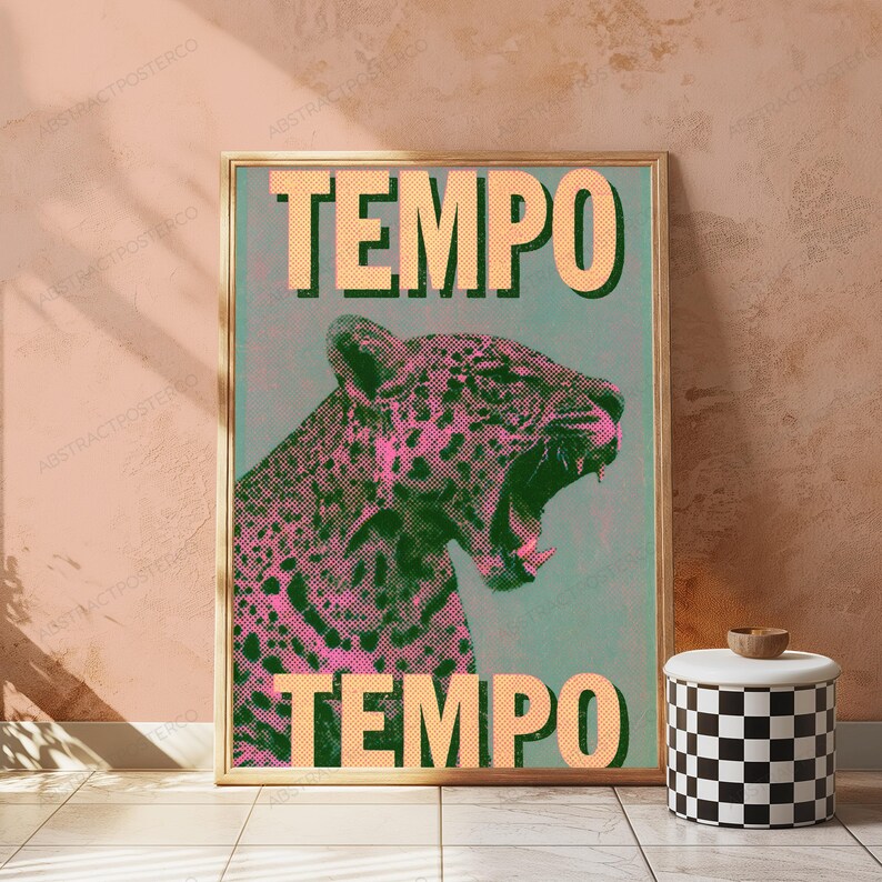 May include: A rectangular wall art print in a wooden frame featuring a stylized leopard with pink and black spots against a muted green background. The word TEMPO is printed in large, bold, light orange letters at both the top and bottom of the print.