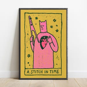 Puede incluir: Una l&aacute;mina de arte rectangular que muestra una figura rosa con orejas puntiagudas sosteniendo unas tijeras. La figura tiene una mancha oscura en forma de coraz&oacute;n en el pecho. Fondo amarillo mostaza con estrellas verde oscuro y el texto A STITCH IN TIME.