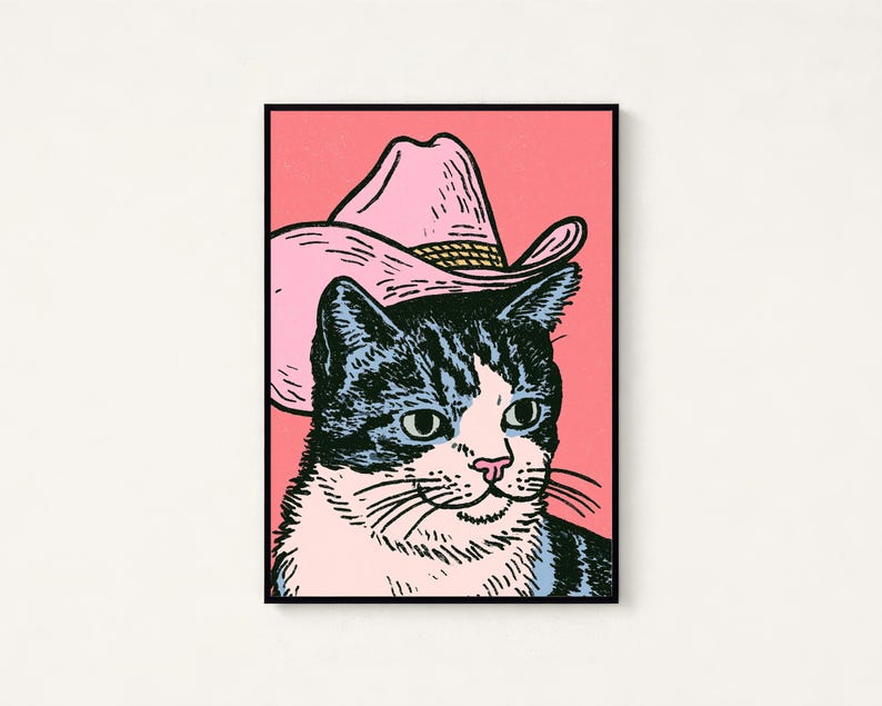 May include: A rectangular wall art print featuring a black and white tabby cat wearing a light pink cowboy hat. The cat has green eyes and a pink nose, set against a solid pink background. The illustration uses bold black outlines.