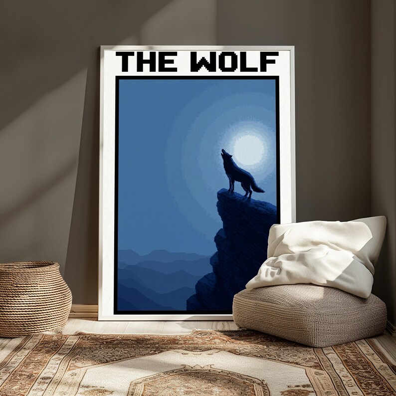 May include: A framed rectangular wall art print featuring a pixelated illustration of a wolf howling at a full moon from a cliff edge. The artwork uses shades of blue and black, with the text THE WOLF printed in a bold, black pixelated font at the top.