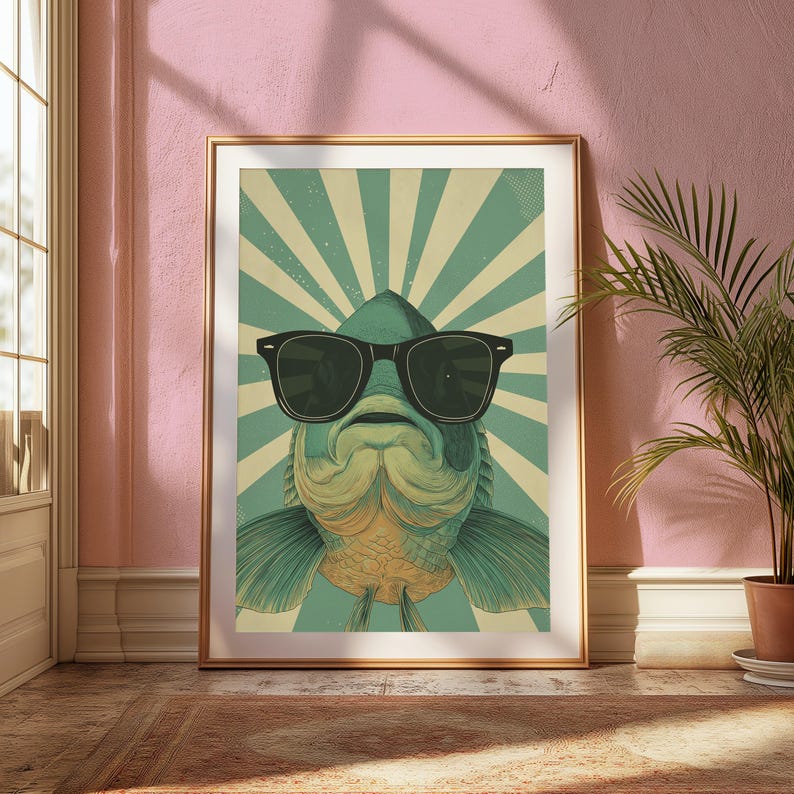 May include: A framed wall art print featuring a stylised illustration of a fish wearing large black sunglasses. The fish is centred against a background of alternating light cream and teal sunburst rays, creating a graphic, symmetrical composition.