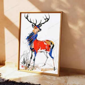 K&ouml;nnte beinhalten: Ein gerahmter Kunstdruck mit einer stilisierten Hirschillustration, die durch kr&auml;ftige, ausdrucksstarke Pinselstriche in leuchtendem Rot, Blau und Schwarz auf wei&szlig;em Grund besticht. Das Bild enth&auml;lt ein kleines rotes quadratisches Siegel unten links.
