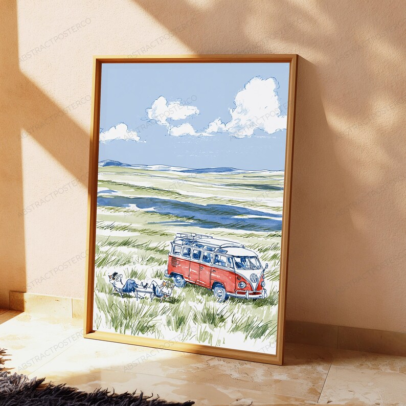 May include: A framed art print featuring a watercolor illustration of a red and white vintage camper van parked in a grassy field. A person sits in a folding chair next to the vehicle under a blue sky with white clouds and distant hills.