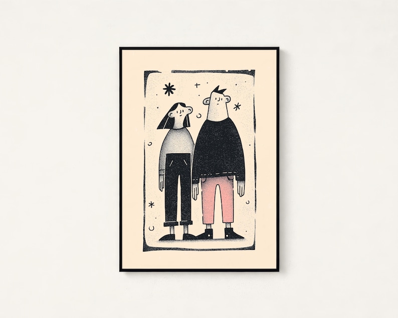 May include: A framed art print featuring a stylised illustration of two figures standing side by side. The figure on the left wears a grey top and black trousers, while the figure on the right wears a black top and pink trousers, set against a cream background.