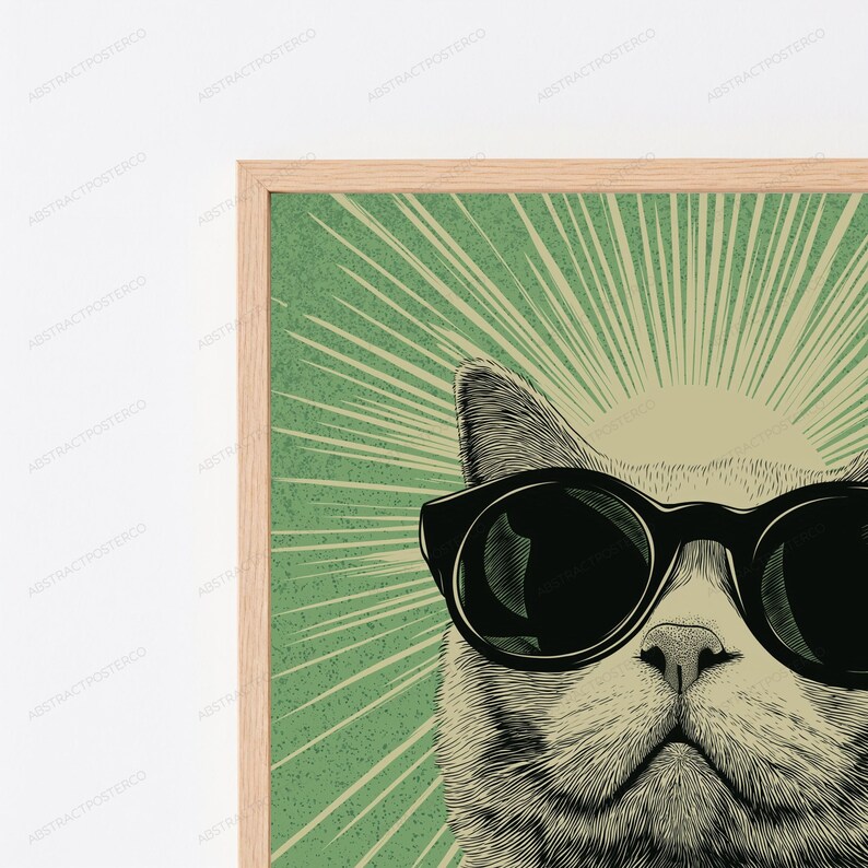 May include: A framed wall art print featuring a detailed illustration of a cat wearing large black sunglasses. The cat is centered against a green background with a radiating sunburst pattern in a lighter shade, all enclosed in a light wood frame.