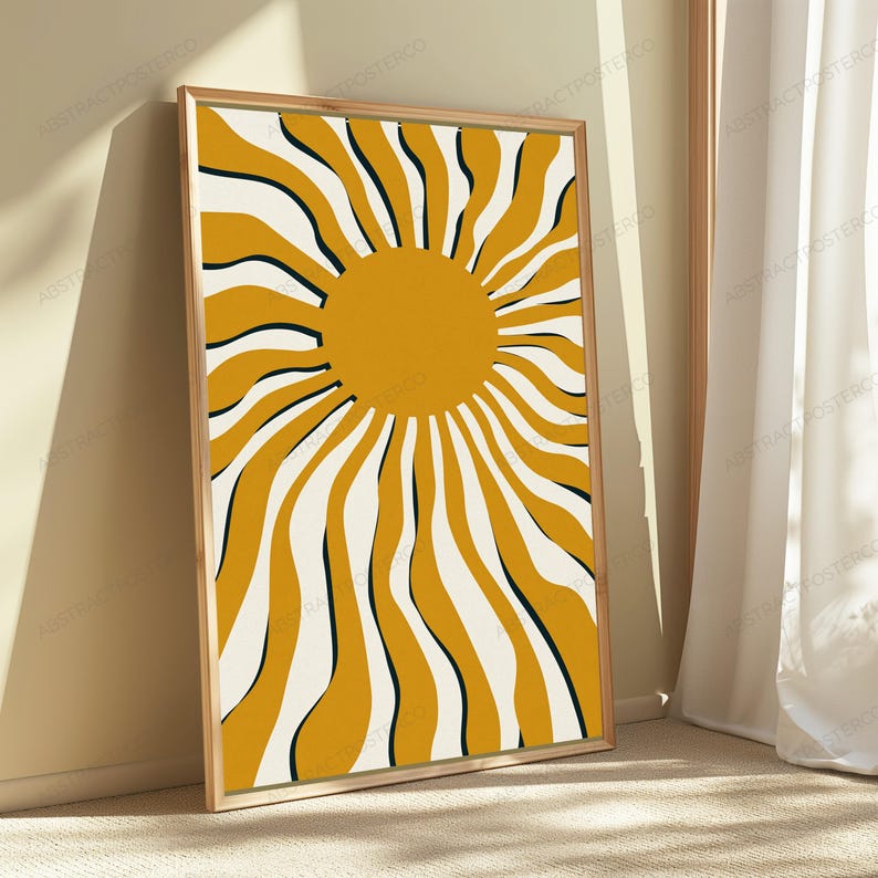 May include: A rectangular framed wall art print featuring a central solid mustard yellow circle surrounded by radiating, wavy mustard yellow and cream-colored stripes. The design is enclosed in a light-toned wooden frame with a clean edge.