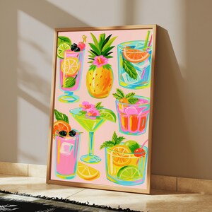 K&ouml;nnte beinhalten: Ein gerahmter vertikaler Kunstdruck auf hellrosa Hintergrund mit farbenfrohen Illustrationen verschiedener tropischer Cocktails in Gl&auml;sern, einer zentralen Ananas mit rosa Bl&uuml;te sowie diversen Zitrusfr&uuml;chten und gr&uuml;nen Minzbl&auml;ttern.