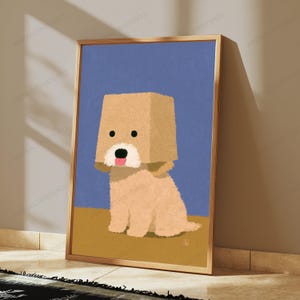 May include: A framed digital illustration of a light brown dog with a square-shaped head, black eyes, a white muzzle, and a pink tongue, set against a solid blue background with a tan floor, enclosed in a thin metallic gold frame.