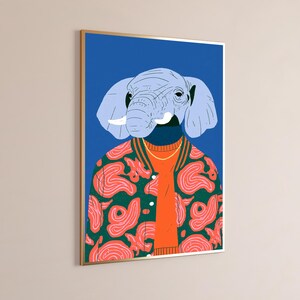 May include: A framed wall art print featuring a stylized illustration of an elephant head with light blue skin and white tusks. The elephant wears a dark green varsity jacket with a pink abstract pattern over a bright orange sweater.
