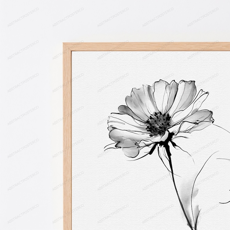 May include: A framed wall art print featuring a black and white ink wash illustration of a single flower with delicate petals and a dark centre. The artwork is encased in a light-toned wooden frame, showcasing a clean and simple aesthetic.