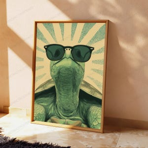 May include: A framed wall art print featuring a green turtle wearing black sunglasses. The turtle is centered against a light yellow background with a radiating sunburst pattern in teal dots. The artwork has a distinct graphic illustration style.