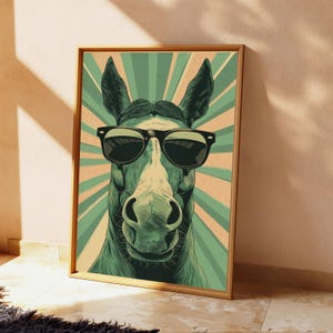 K&ouml;nnte beinhalten: Ein gerahmter Wandkunstdruck mit einer stilisierten Illustration eines Pferdes, das eine schwarze Sonnenbrille tr&auml;gt. Das Pferd ist vor einem Hintergrund aus abwechselnd hellgr&uuml;nen und beigen Sonnenstrahlen im Grafikstil zentriert.